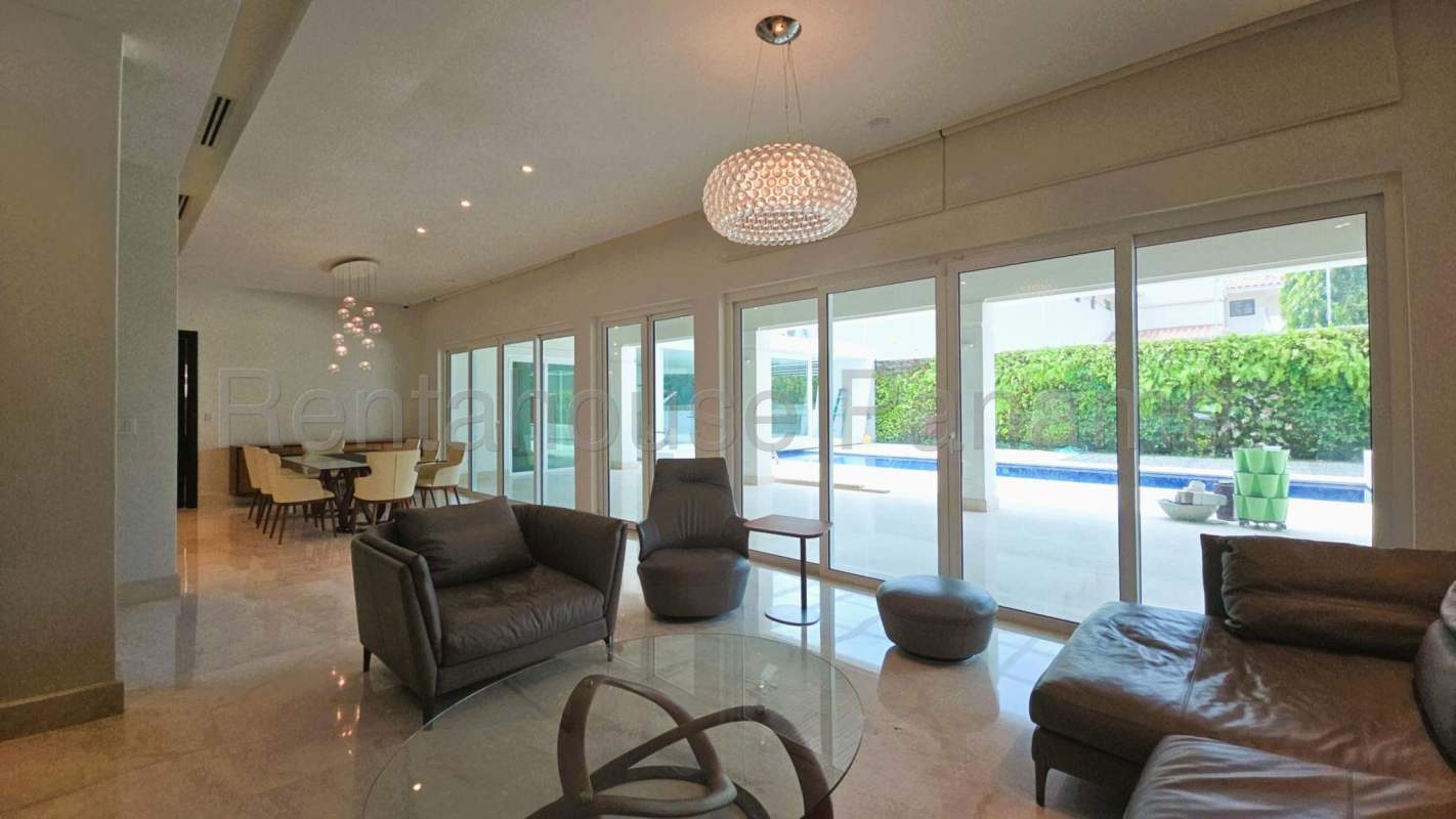 Modern dining area with glass table, pendant lights, and large windows in Toscana del Este Panama