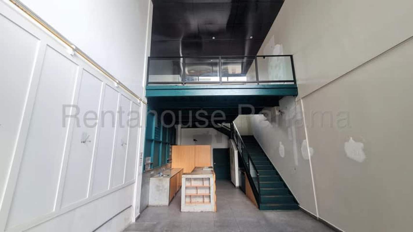 Double height open commercial space with teal stairs, kitchen island, metal railing in PH San Francisco Plaza
