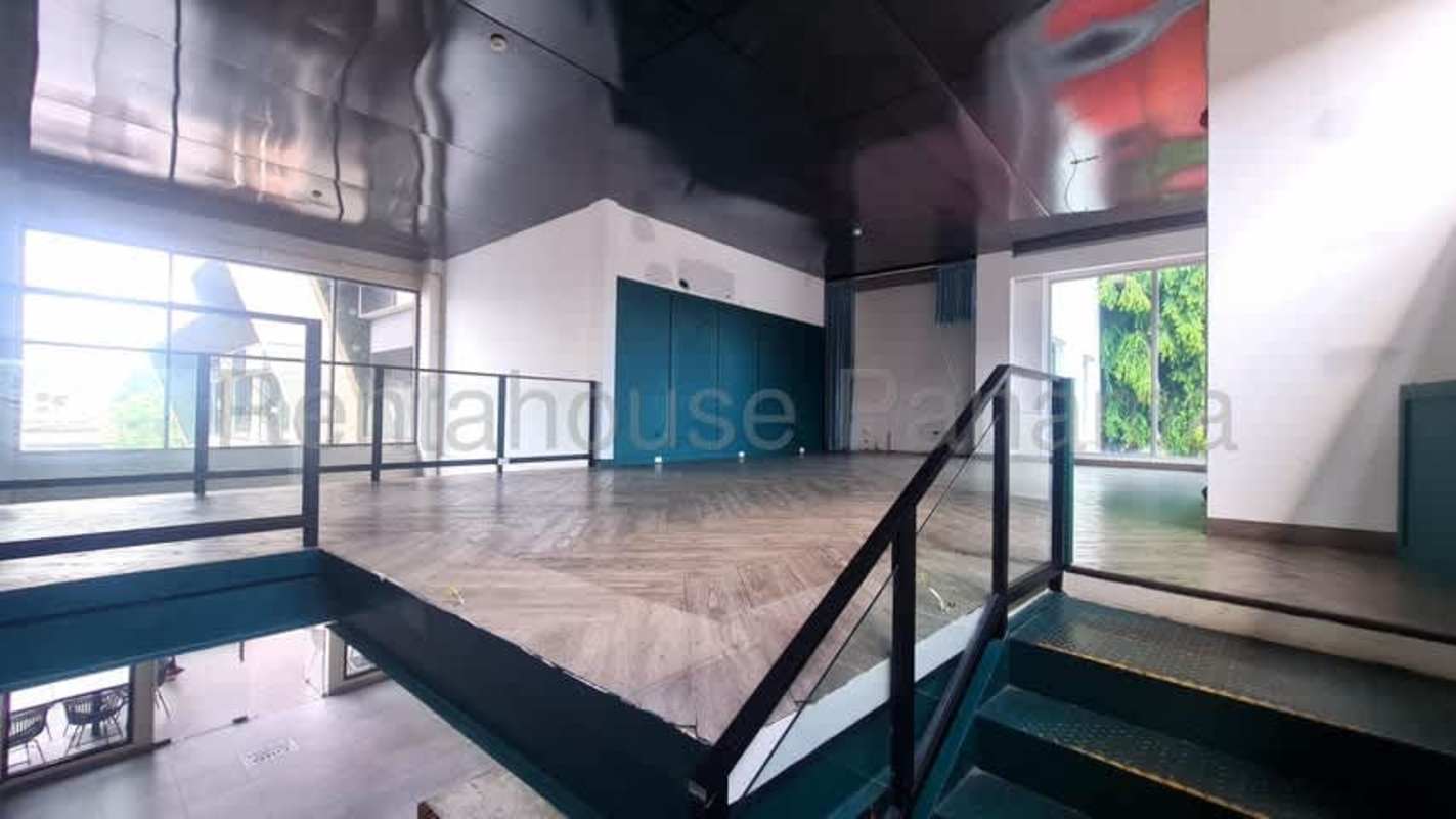 Stylish commercial space with herringbone wood floor, black ceiling, teal wall Panama City