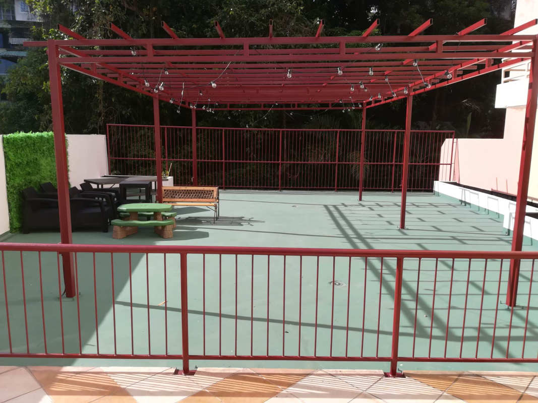 Outdoor terrace with red pergola, seating area and green flooring PH Bella Vista Garden Panama