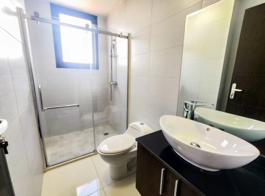 Modern bathroom with vessel sink, glass-enclosed shower, natural light PH Cosmopolitan Panama