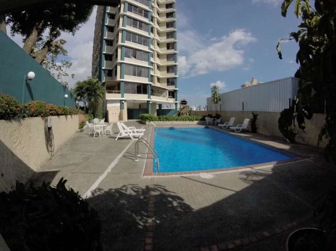 Condominium pool with deck chairs and tower building in PH Miraflores Villa de las Fuentes Panama
