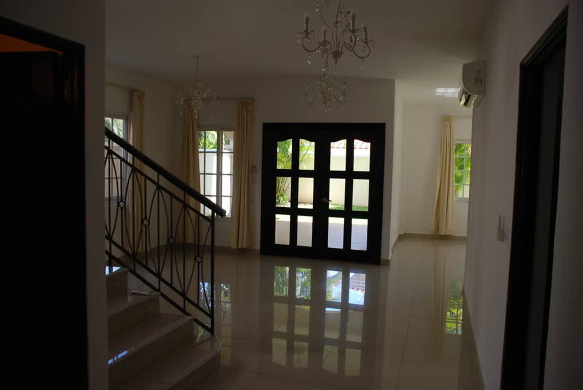 Spacious living room with tiled floors, decorative chandelier and metal staircase in Costa Sur Panama house