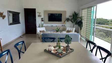 Bright dining area adjacent to furnished living room with balcony view