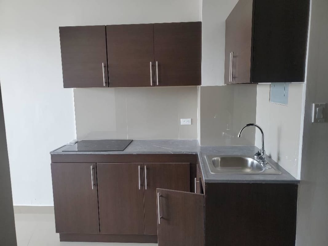 Compact kitchen with brown cabinets, stove, tile backsplash Bay View Panama apartment