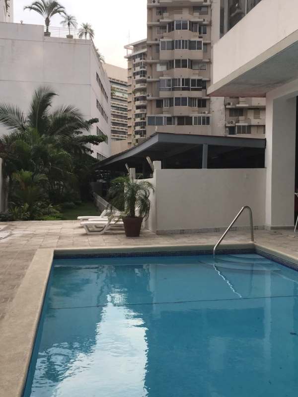 Outdoor swimming pool with sun loungers surrounded by city buildings in PH Parque Marbella Panama City