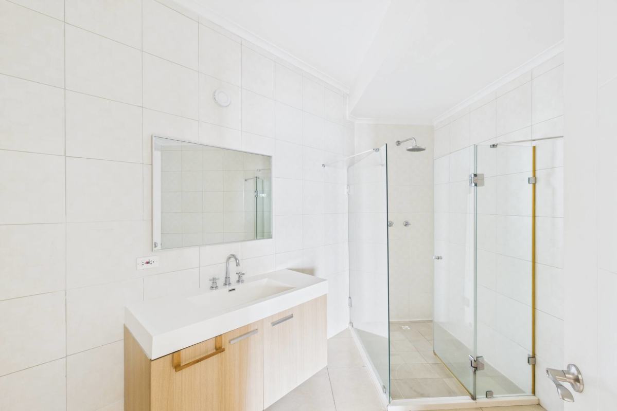 Modern walk-in closet with built-in wood shelves drawers connects to luxury bath