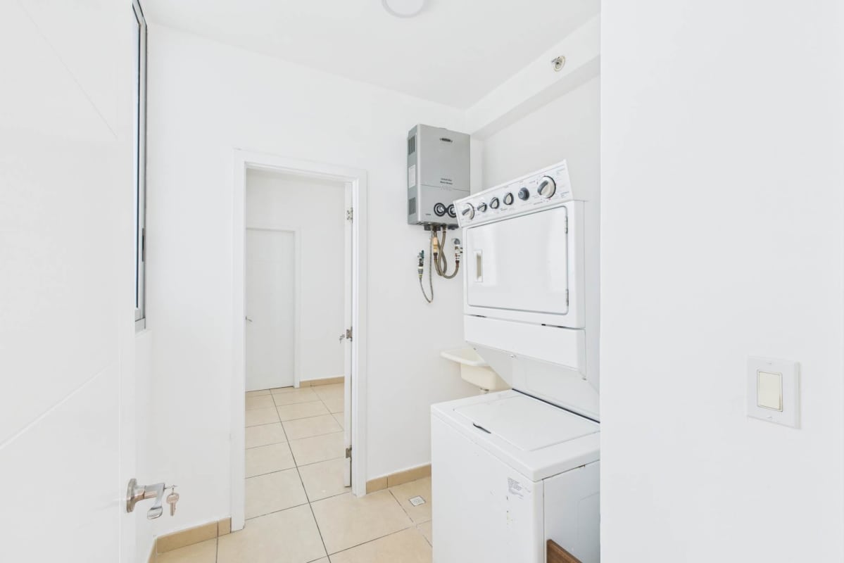 Contemporary laundry with stacked washer dryer tankless heater in Punta Pacifica condo