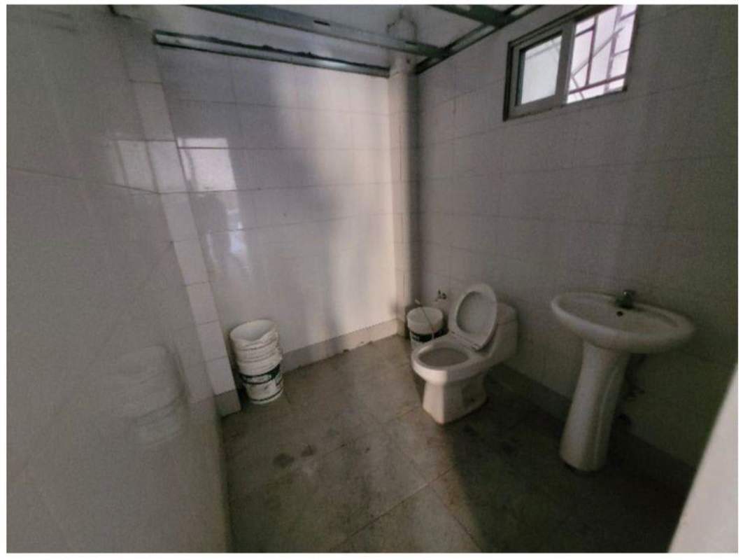 Basic warehouse bathroom with pedestal sink, toilet, tiled walls, ventilation window in Parque Industrial Las Americas Panama