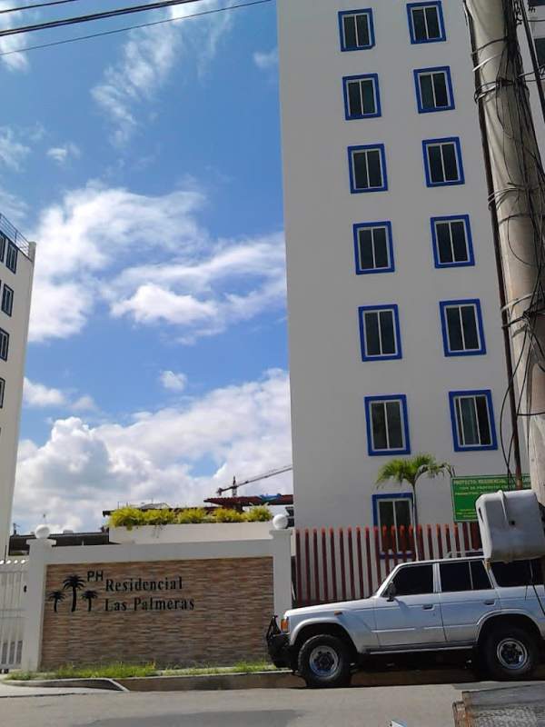 Facade of Residencial Las Palmeras with blue-trimmed windows and secured entrance Panama City