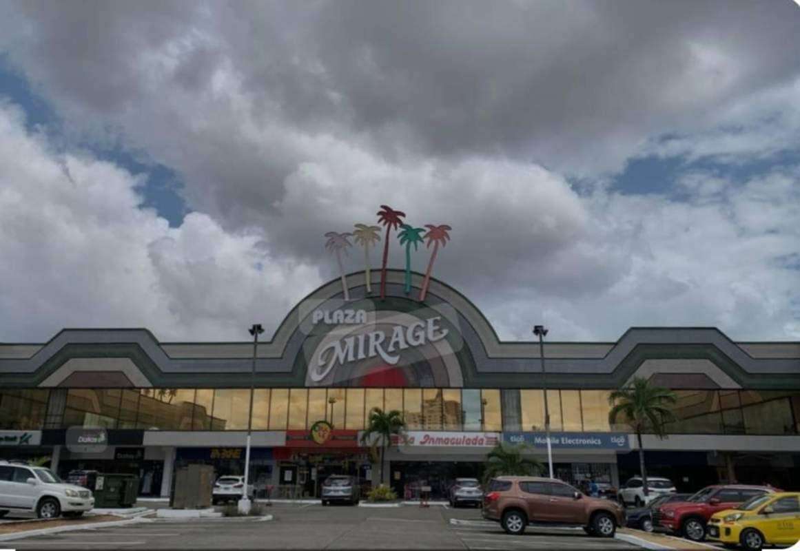 Wide shot of busy commercial plaza with parking, shops and palm signage at Plaza Mirage Panama City