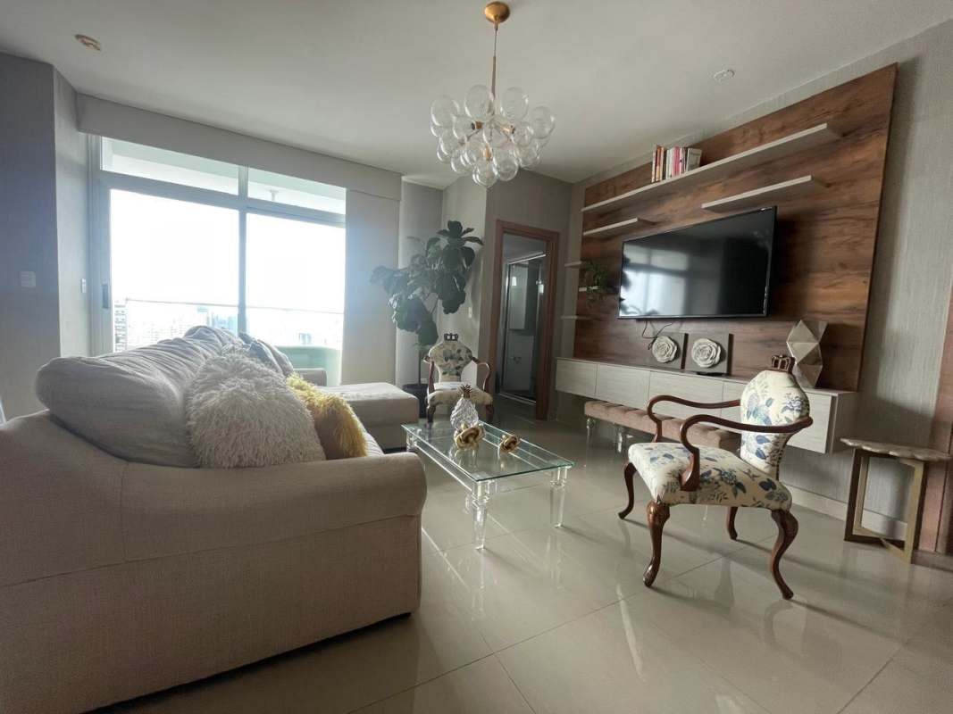 Large windows, cream sofa, mounted TV and balcony in furnished Panama apartment