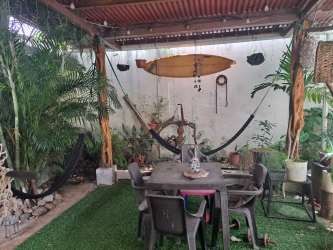 Covered outdoor terrace patio with hammock, dining set, lush plants in La Chorrera rental house