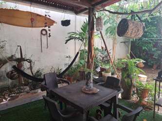 Covered backyard patio with hammocks surfboard and plants in rental house La Chorrera