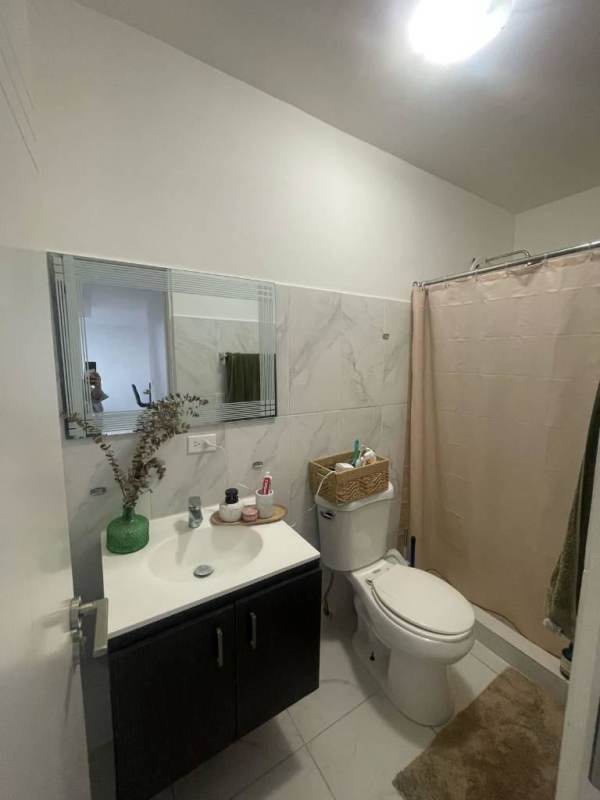 Bathroom with marble wall tile and shower curtain in Panama City apartment