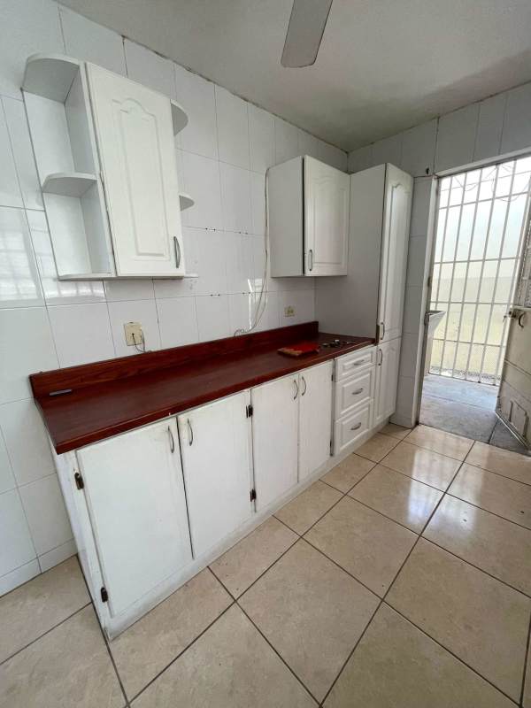 Traditional kitchen with white cabinets, wood counter, cooktop in Brisas del Golf house Panama
