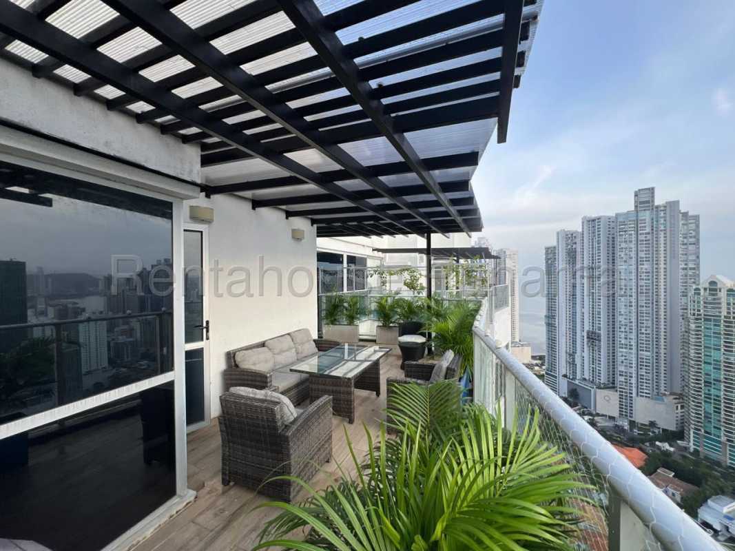 Modern luxury dining room with marble flooring, glass table, floor-to-ceiling windows with city ocean backdrop