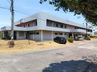 Side exterior view two-story commercial medical building metal siding parking corner Aguadulce