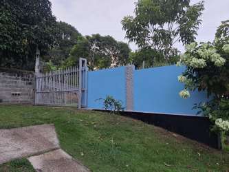 Blue painted house with cyclone fence and front gate on large corner lot in La Chorrera Panama