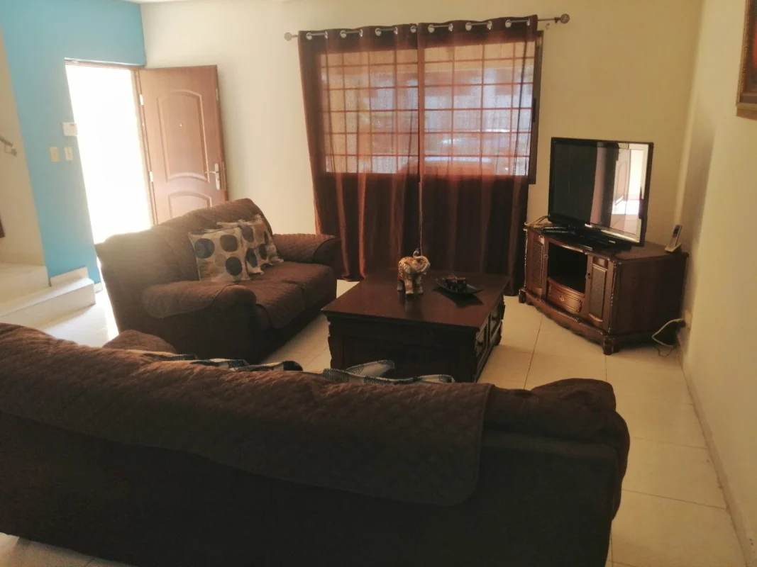 Living room with sofa, TV console, tile floor and bright window Panama