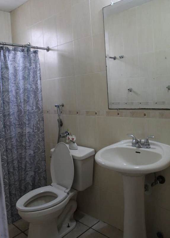 Bathroom with beige tiles, pedestal sink, walk-in shower and mirror in Brisas del Golf Panama