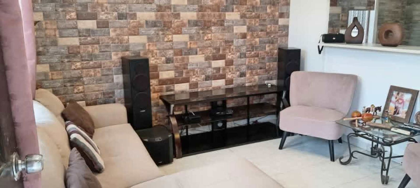Living room with beige sectional sofa, brick accent wall and entertainment center Cerro Viento