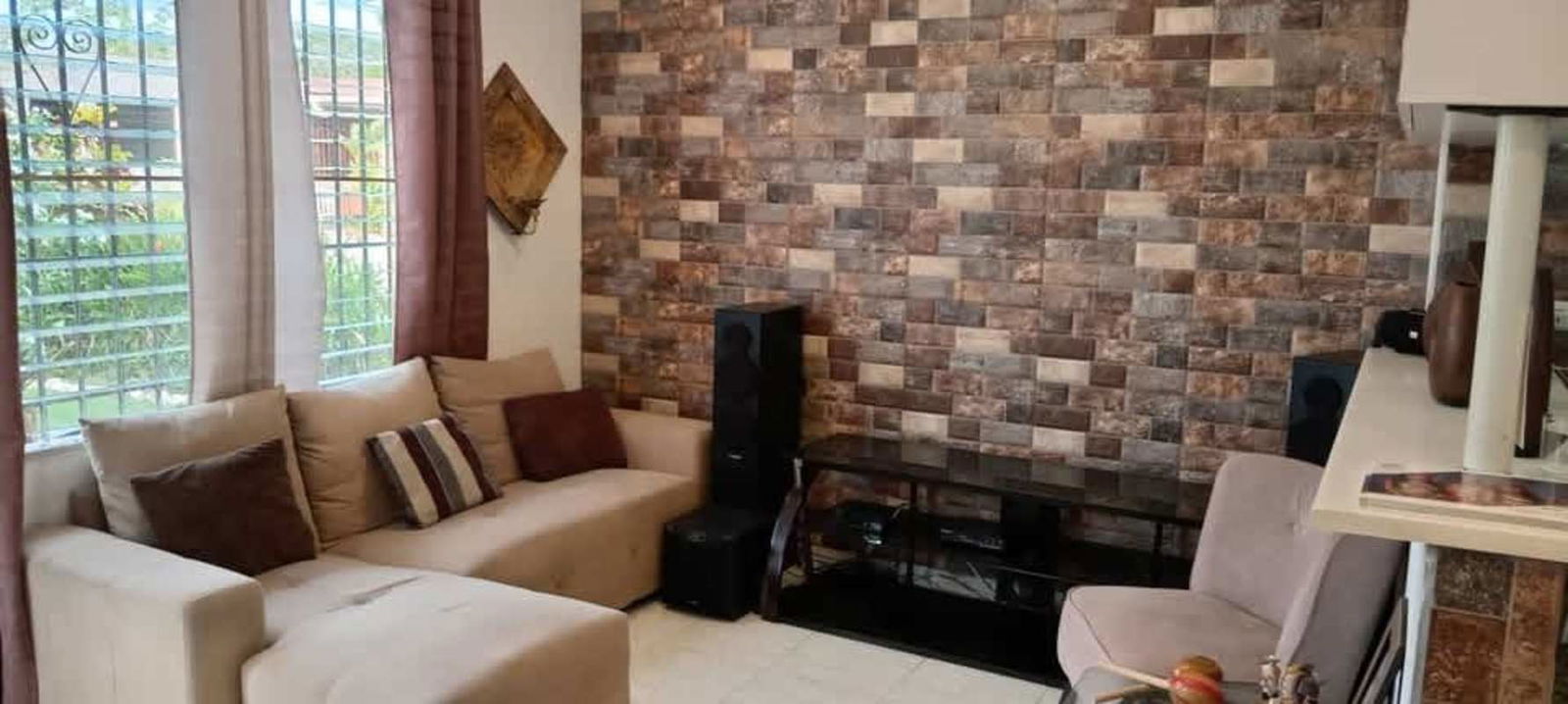 Living space with beige sofa, large windows, security bars and textured accent wall in San Antonio Panama