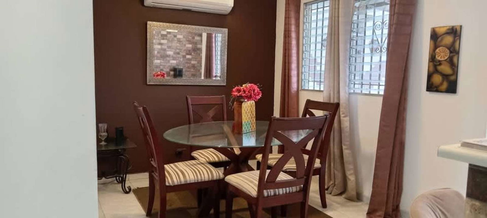 Dining area with glass table, upholstered chairs and wall art in San Antonio Panama