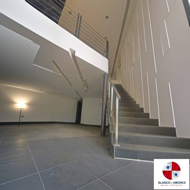 Double-height lobby with staircase and geometric panels inside office building near Costa del Este