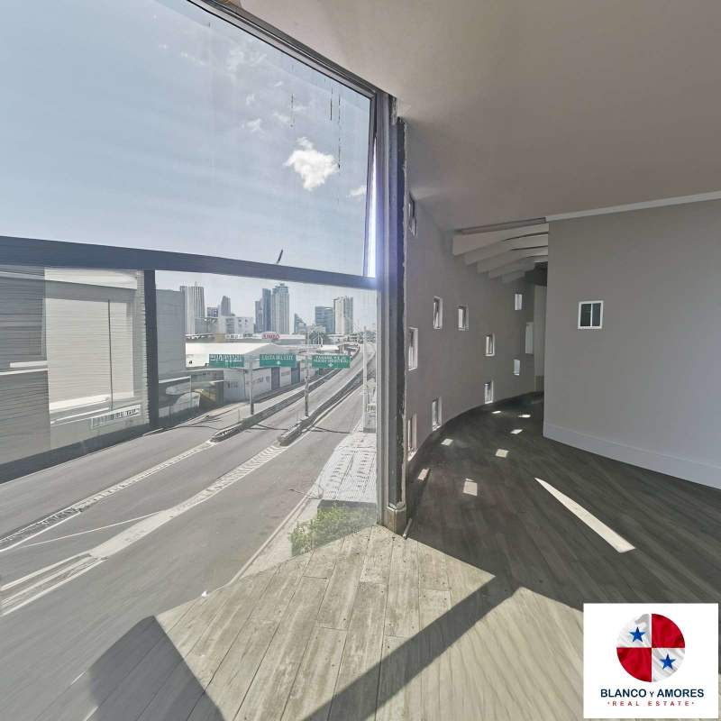 Modern office area with large curved window wall, wood floors and city skyline view in Panama