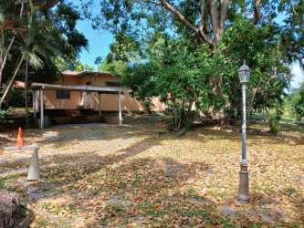 Ranch style single-family home with covered carport surrounded by shade trees and driveway in Coronado Panama