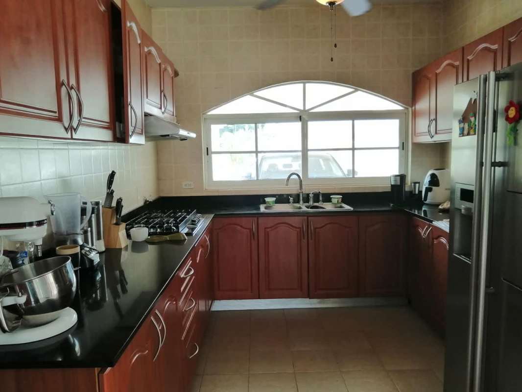 Spacious kitchen with granite countertops, wood cabinets, arch window in Green Field Clayton house Panama
