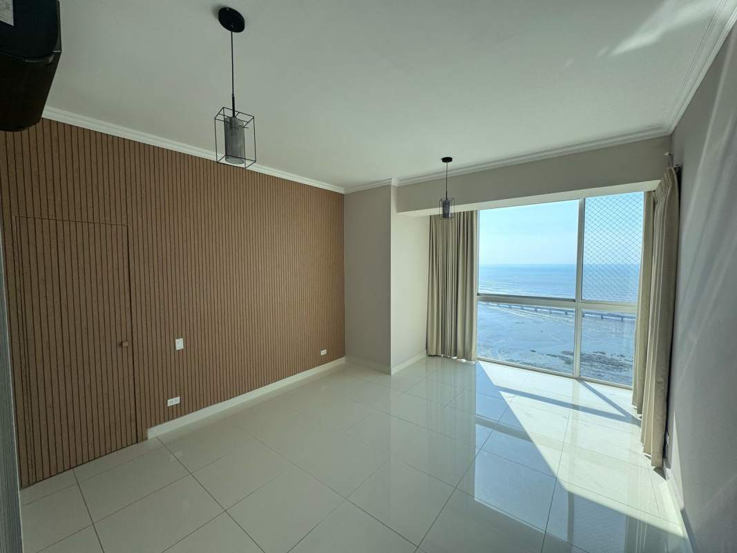 Modern living room with large window and ocean view, wood accent wall and tile floors in PH Nautica Coco del Mar