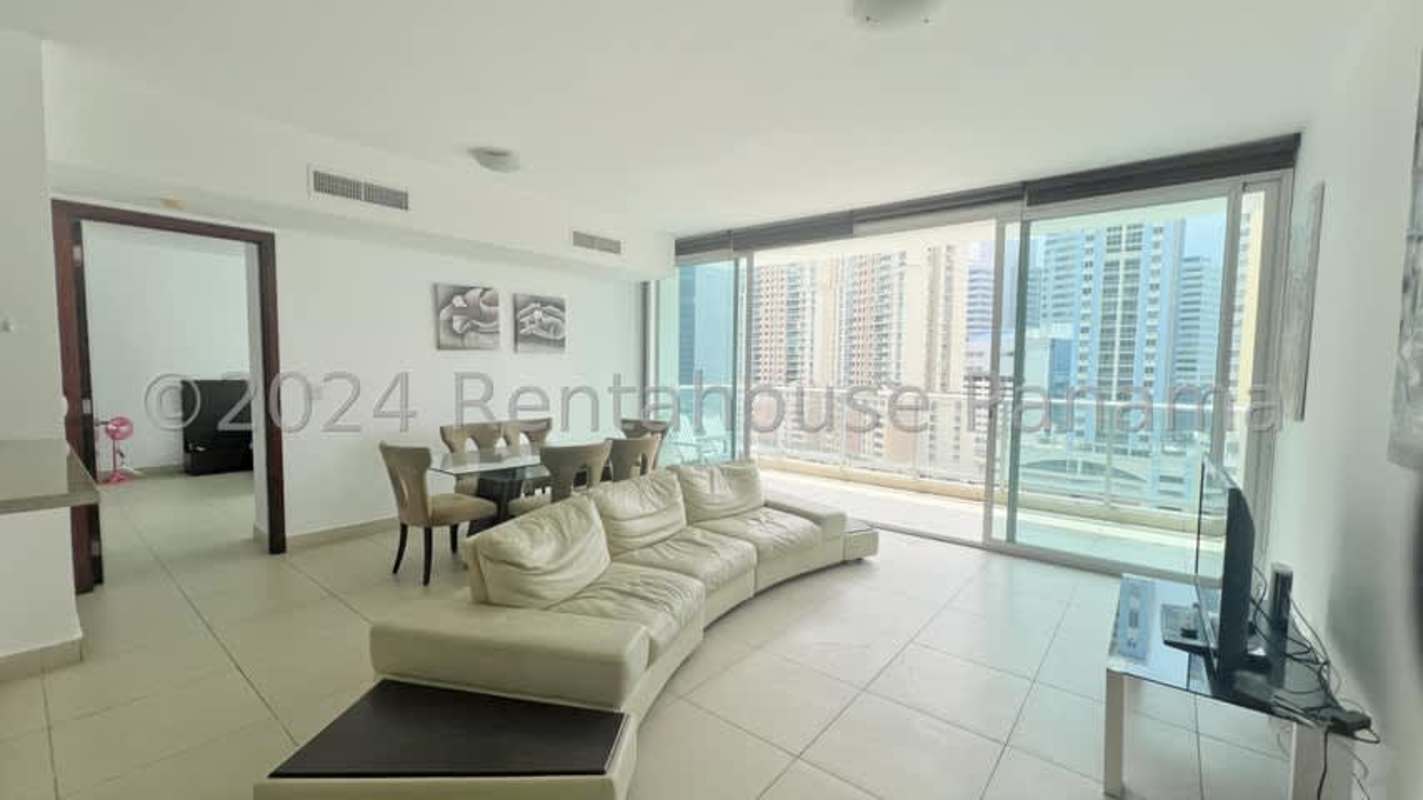 Spacious living room with floor-to-ceiling windows and balcony overlooking Panama skyline and ocean