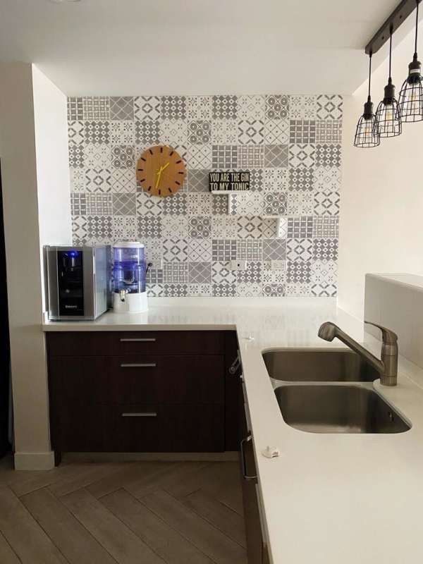 Modern kitchen interior with patterned backsplash, wooden cabinets, double sink, pendant cage lights in PH El Carmen Tower Panama
