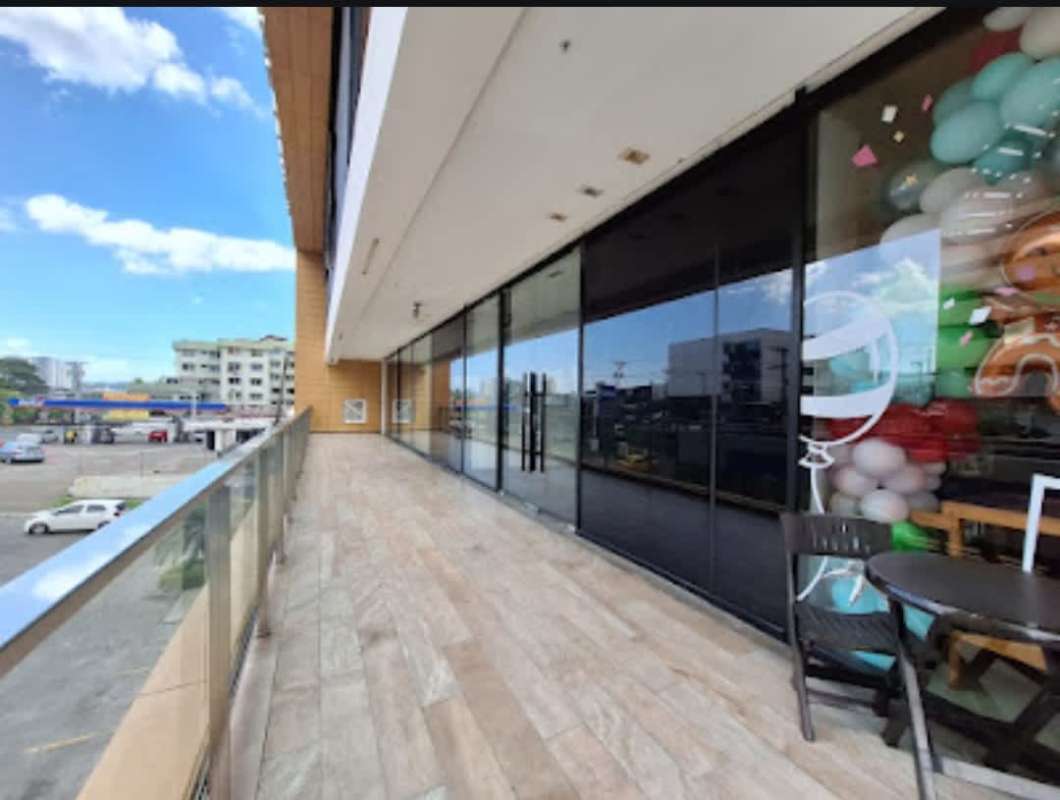 Shopping plaza with glass railing balcony and store entrances in Plaza Liberty Panama