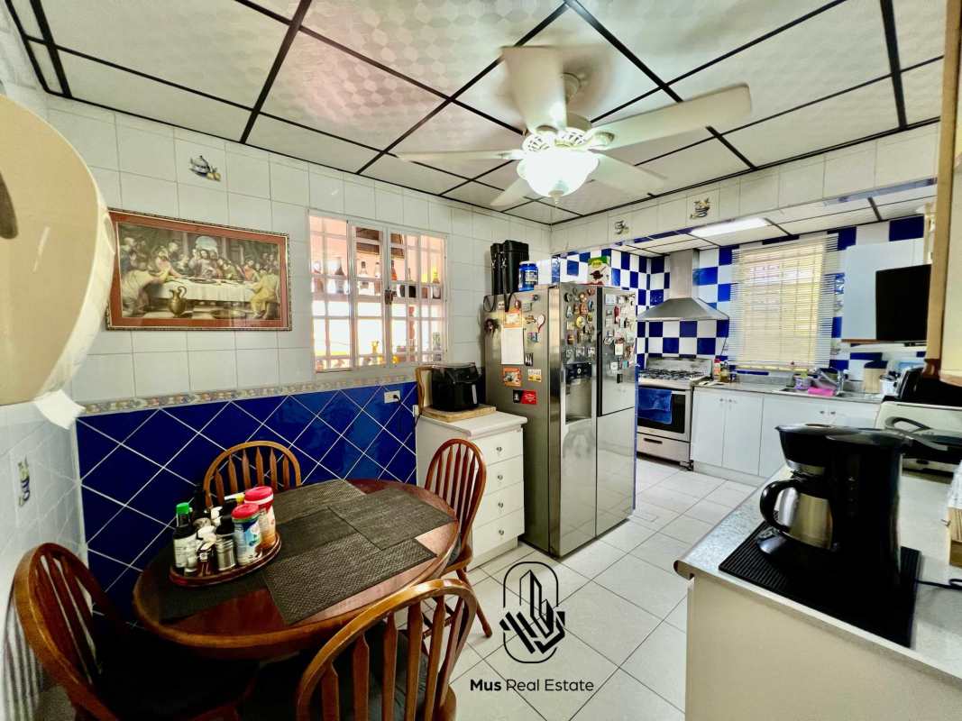 Functional kitchen with blue and white tiles, appliances, and breakfast corner in Brisas del Golf Panama