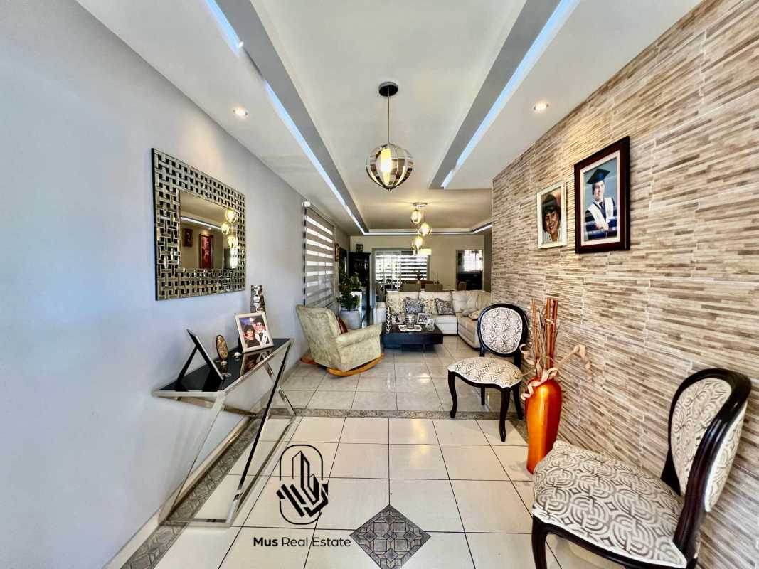 Contemporary living room with beige sectional, tiled flooring, accent walls and modern lighting in Brisas del Golf Panama