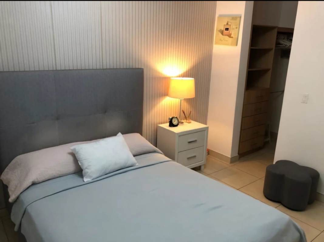 Modern bedroom with upholstered headboard, walk-in closet area Punta Pacifica Panama