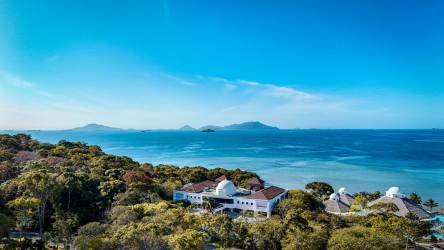 Aerial view of Mediterranean beachfront villas surrounded by jungle with Pacific Ocean view