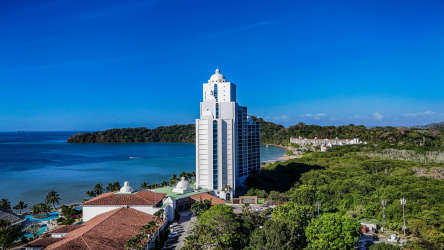 Aerial of beachfront modern high-rise surrounded by greenery and pool Playa Bonita Panama
