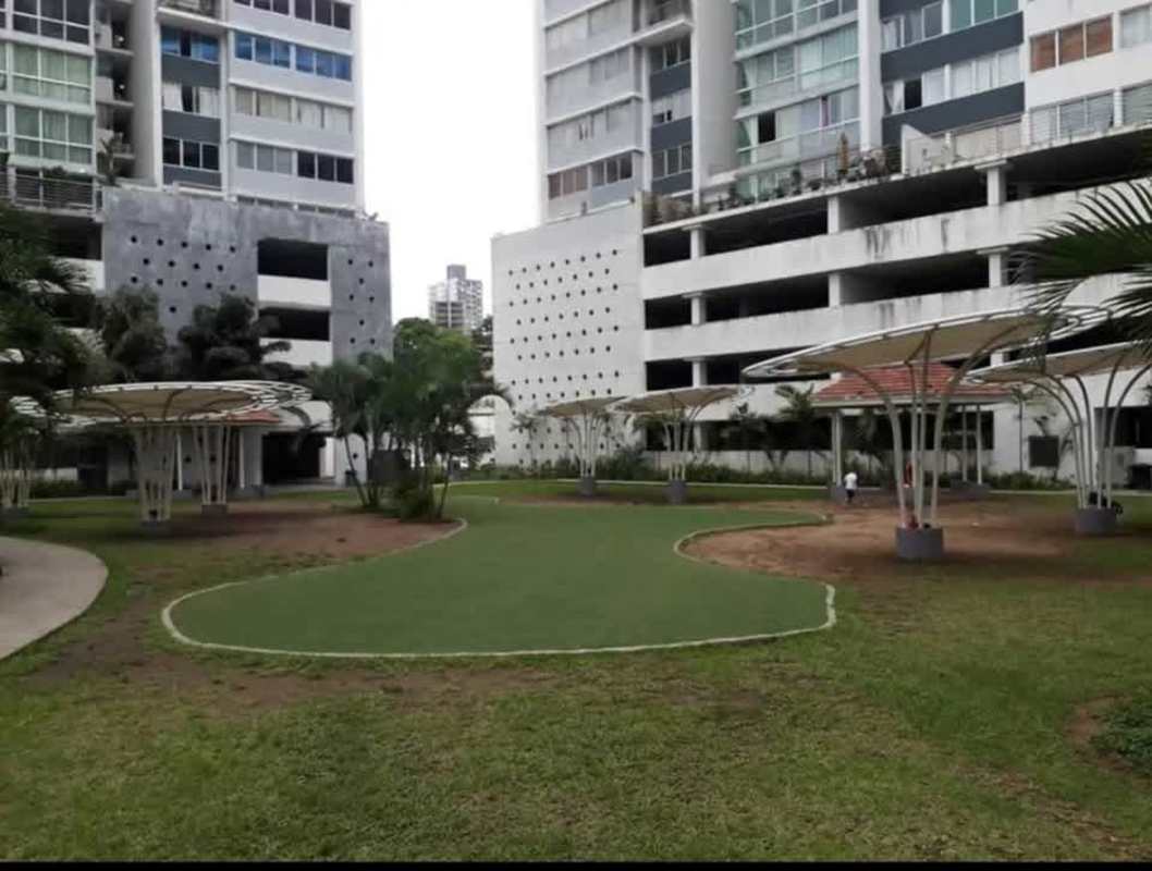Modern apartment complex courtyard green lawn palm trees shaded seating structures in Central Park Panama City