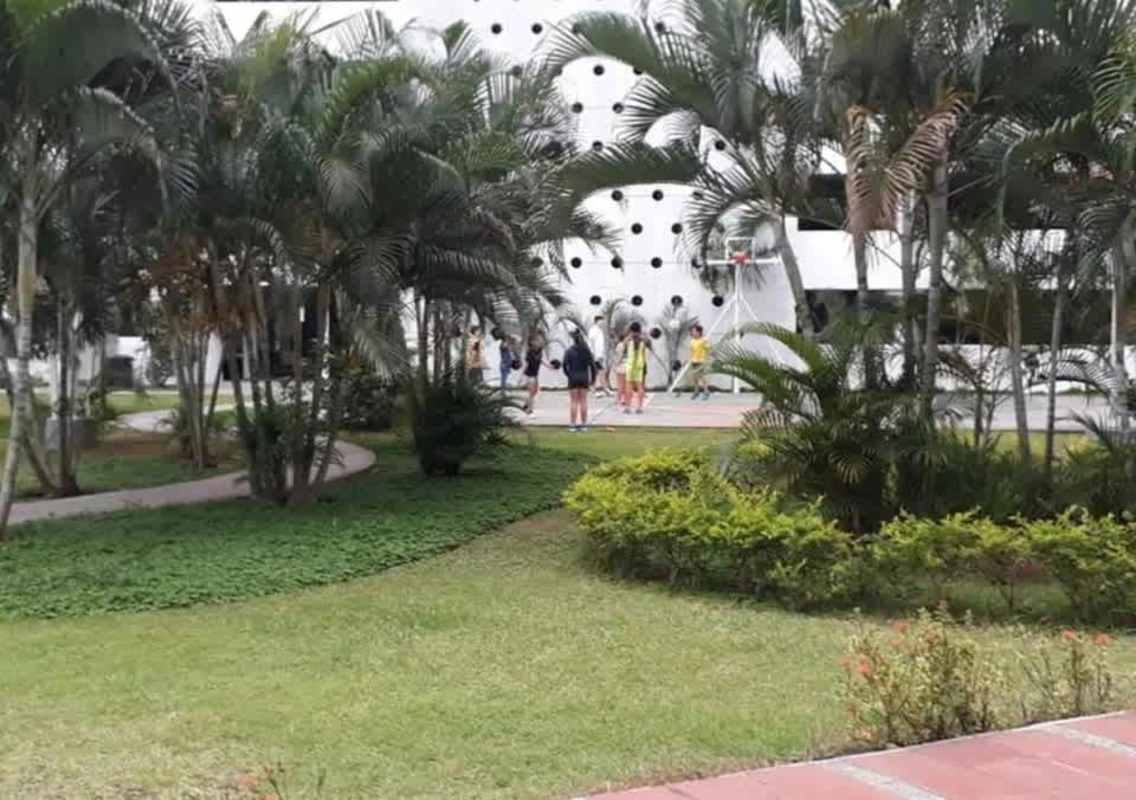 Residential building with gardens, palm trees, and basketball court at Central Park 12 Octubre Metro Panama