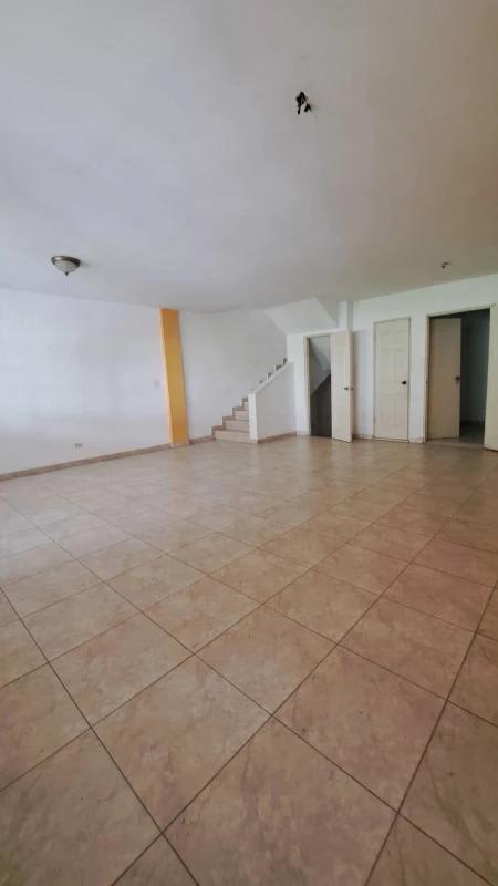 Large open plan living space with staircase, orange feature wall, tiled floor in Altos de Santa María home Panama