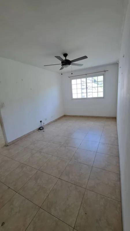 Bright living area with beige tile floor, large window, ceiling fan in family house Altos de Santa María Panama City
