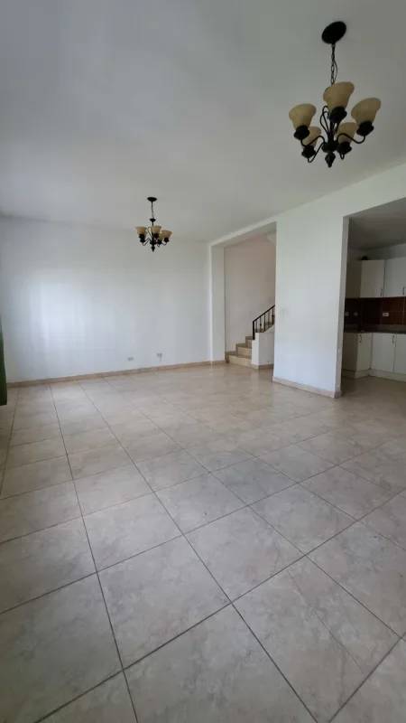 Empty open living room with tiled floors, chandeliers, staircase in Altos de Santa María house Panama City