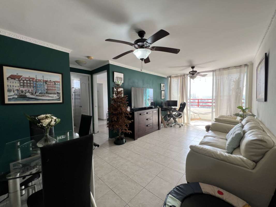 Furnished dining space featuring glass table, green accent wall, ceiling fans and balcony view in PH El Marquez Panama