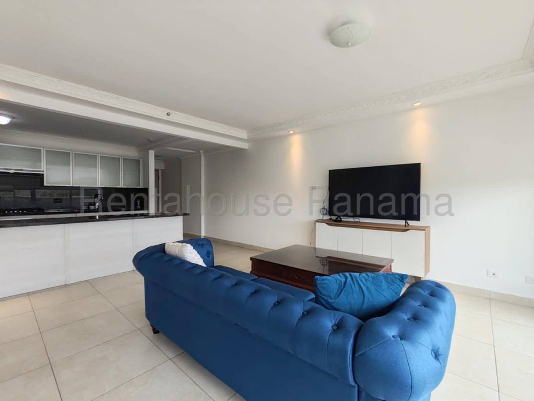 Living room with blue sofa, flat-screen TV, open kitchen with granite counters Clayton Panama