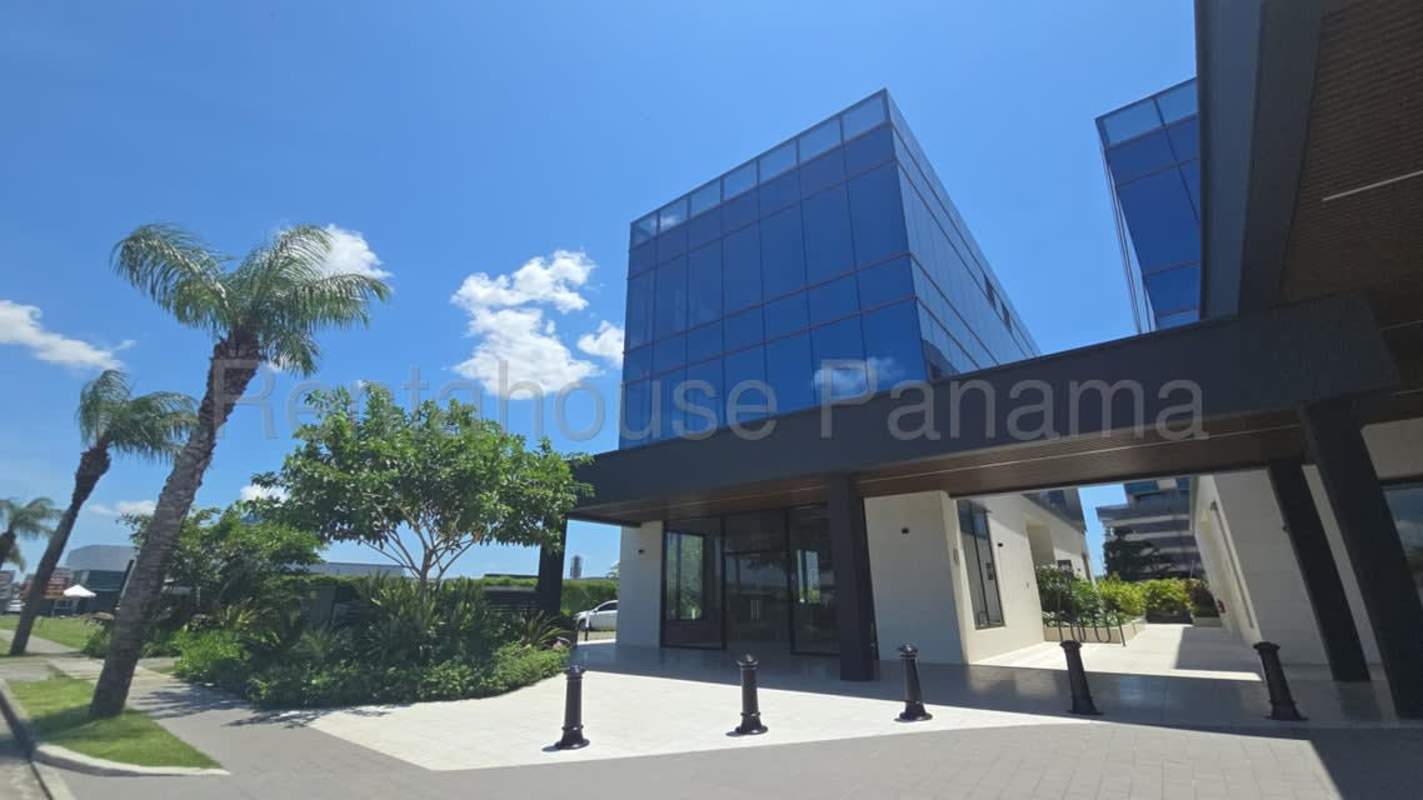Elegant glass-facade commercial building amid palm trees and landscaped entrance at Santa María Panama