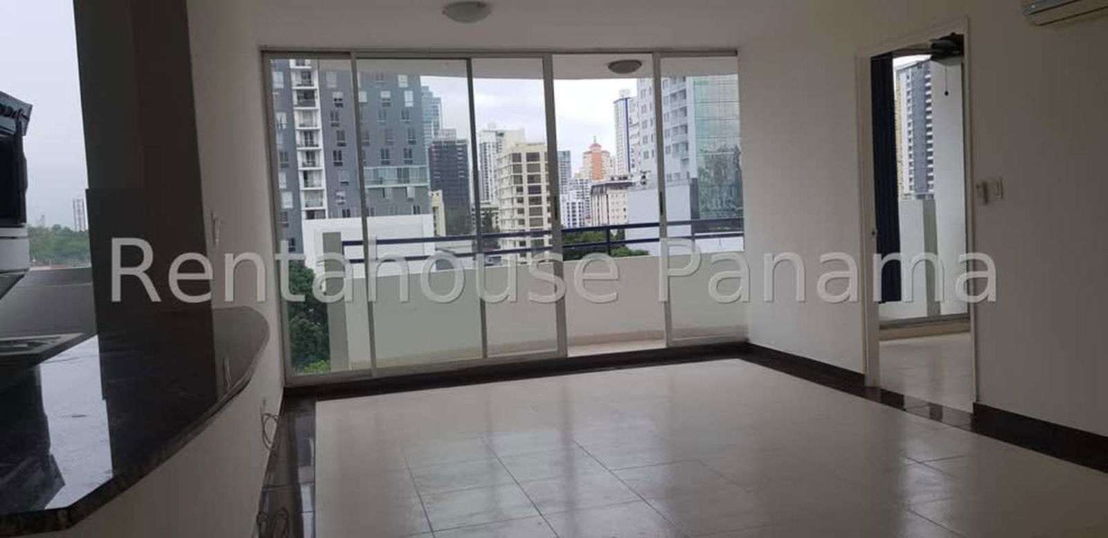 Bright living room with large glass doors leading to balcony overlooking skyline in PH San Francisco Panama City